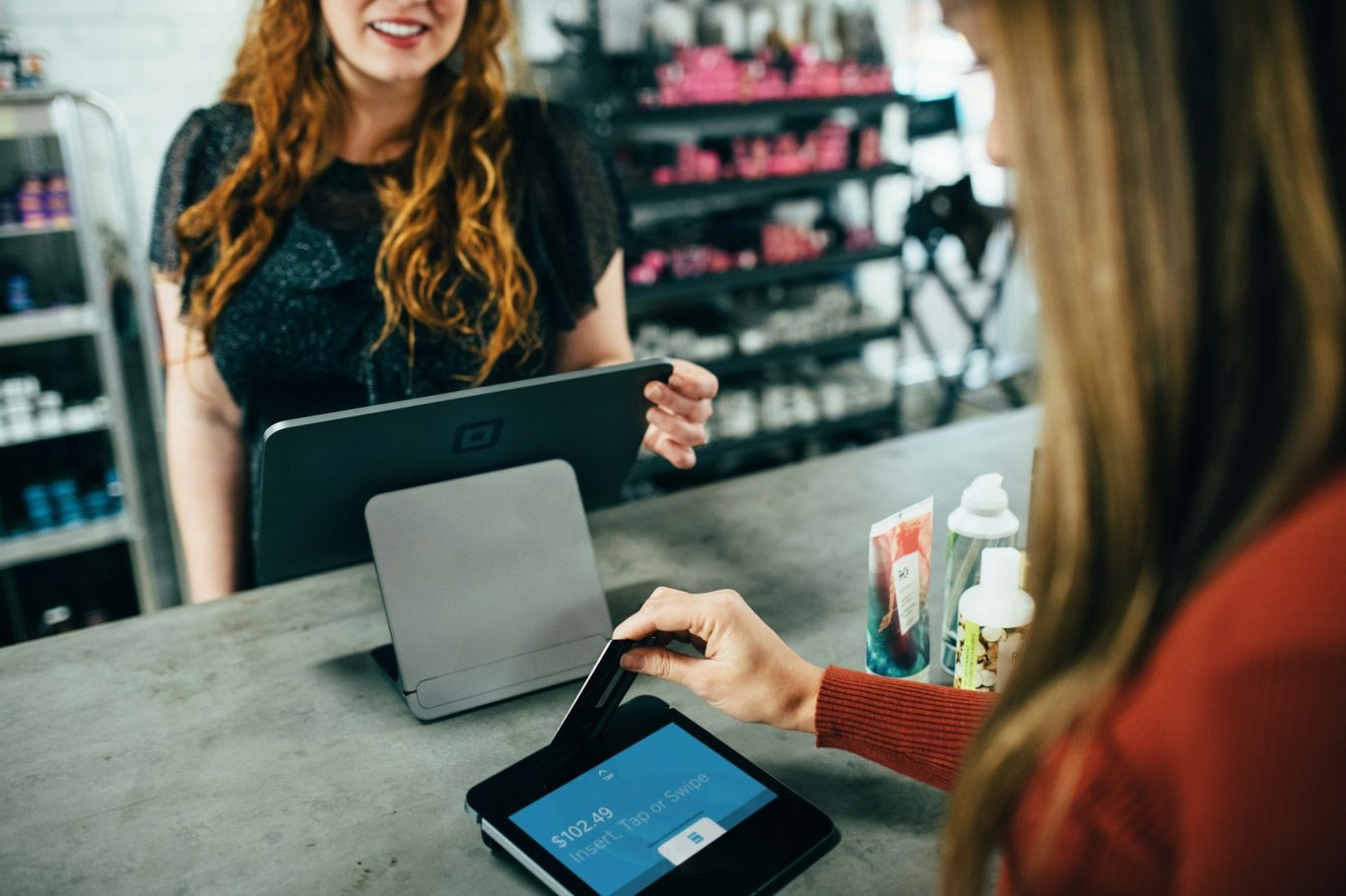 Zwei Frauen sitzen am Tisch und unterhalten sich, beide mit Tablets.